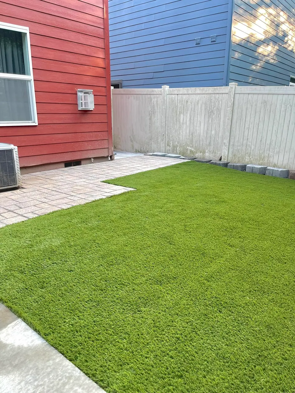 Artificial turf lawn framed by a paver border and patio