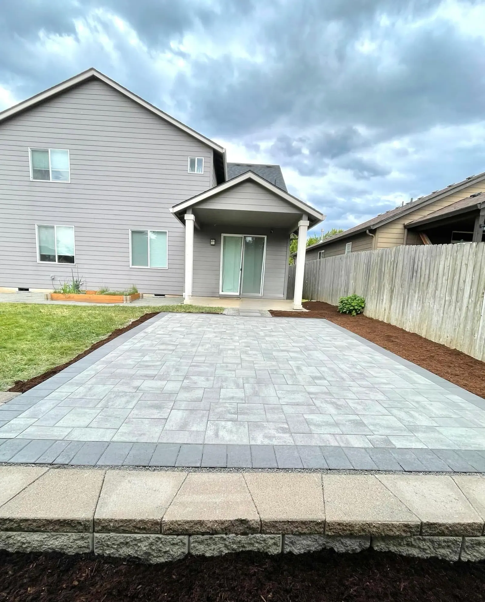 Large format paver patio installed behind a two-story home