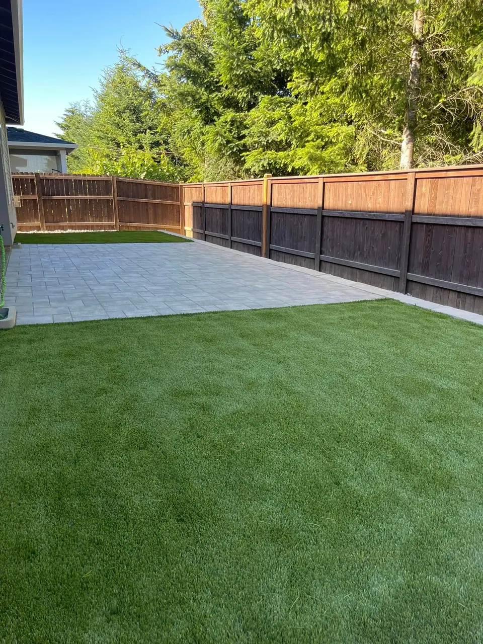 Paver patio and artificial turf combined in a fenced backyard