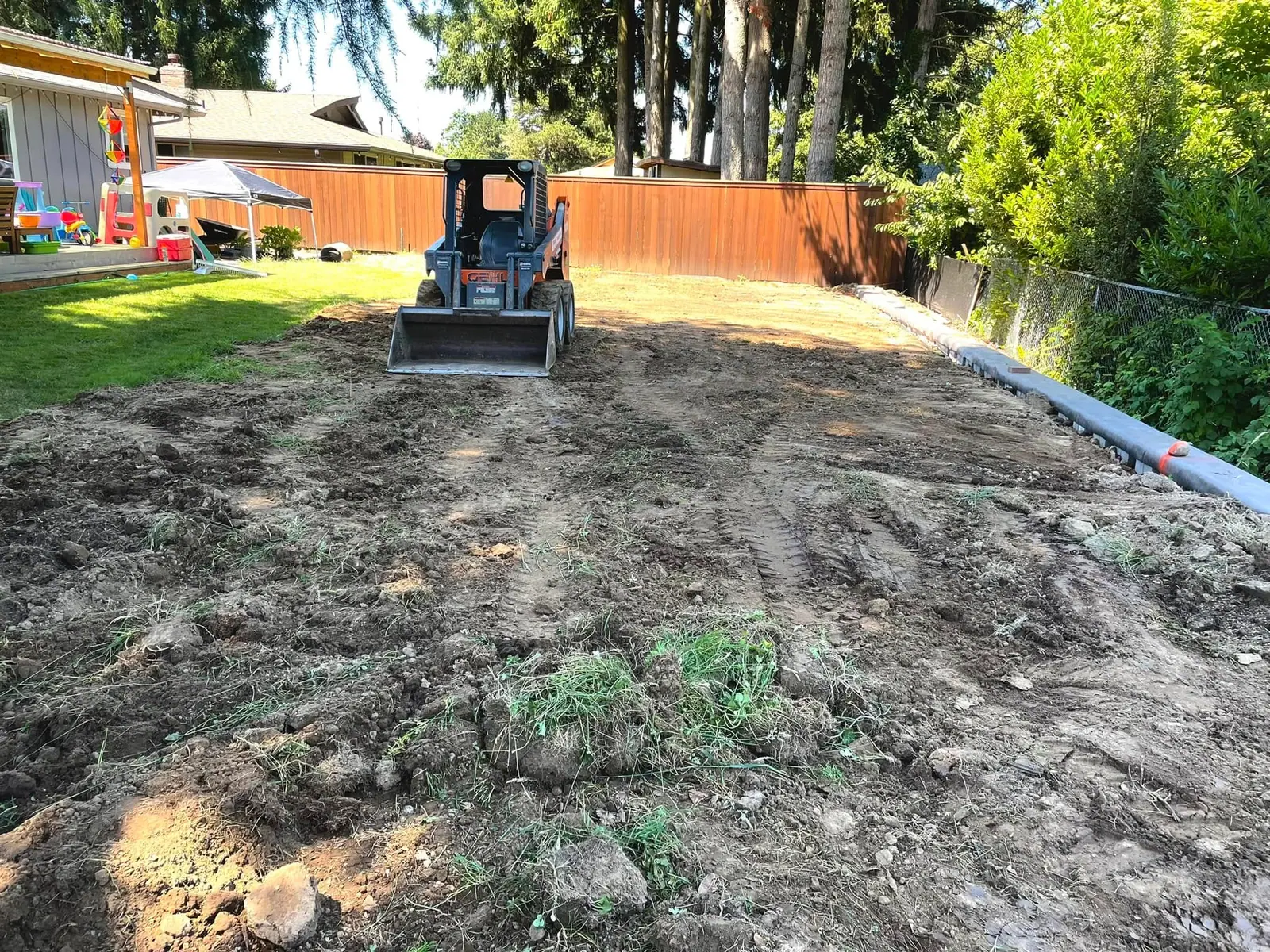 Skid steer grading a sloped lot for a new landscape